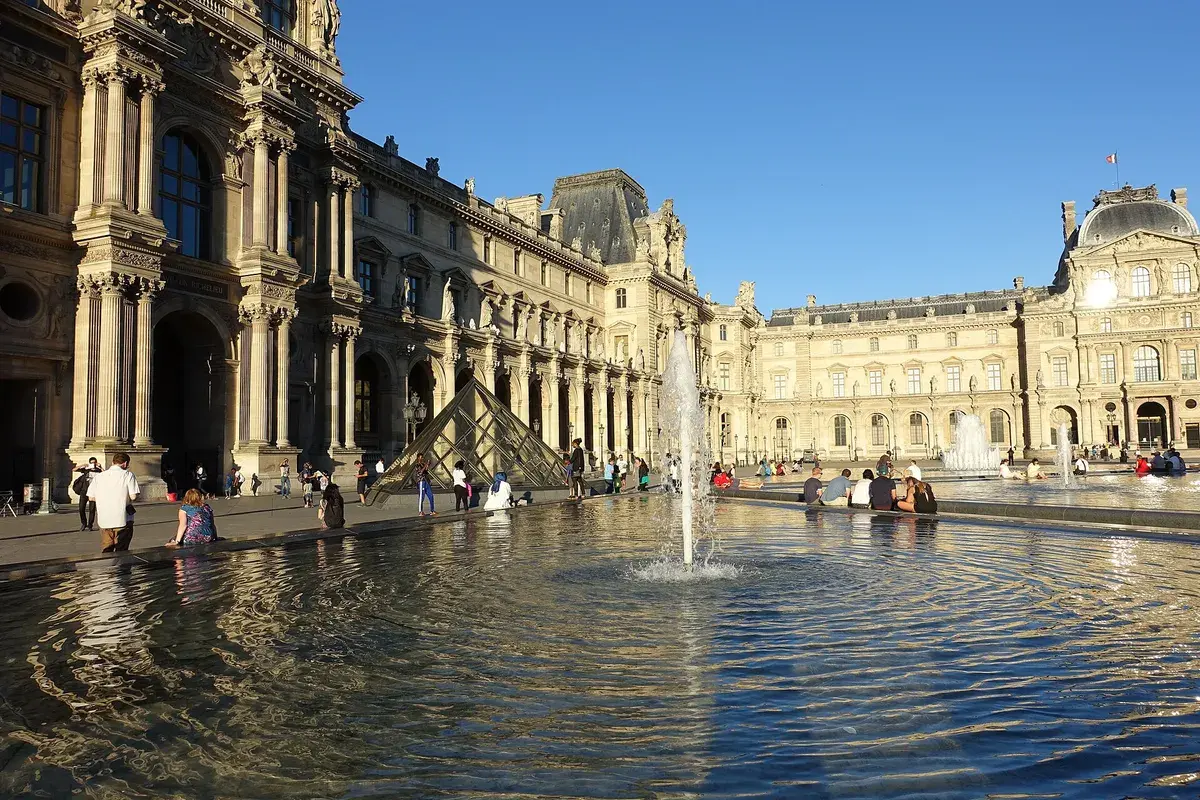 A fountain in the Cour Napoléon at the Louvre, with the palace wings behind. Photo: Guilhem Vellut, CC BY 2.0
