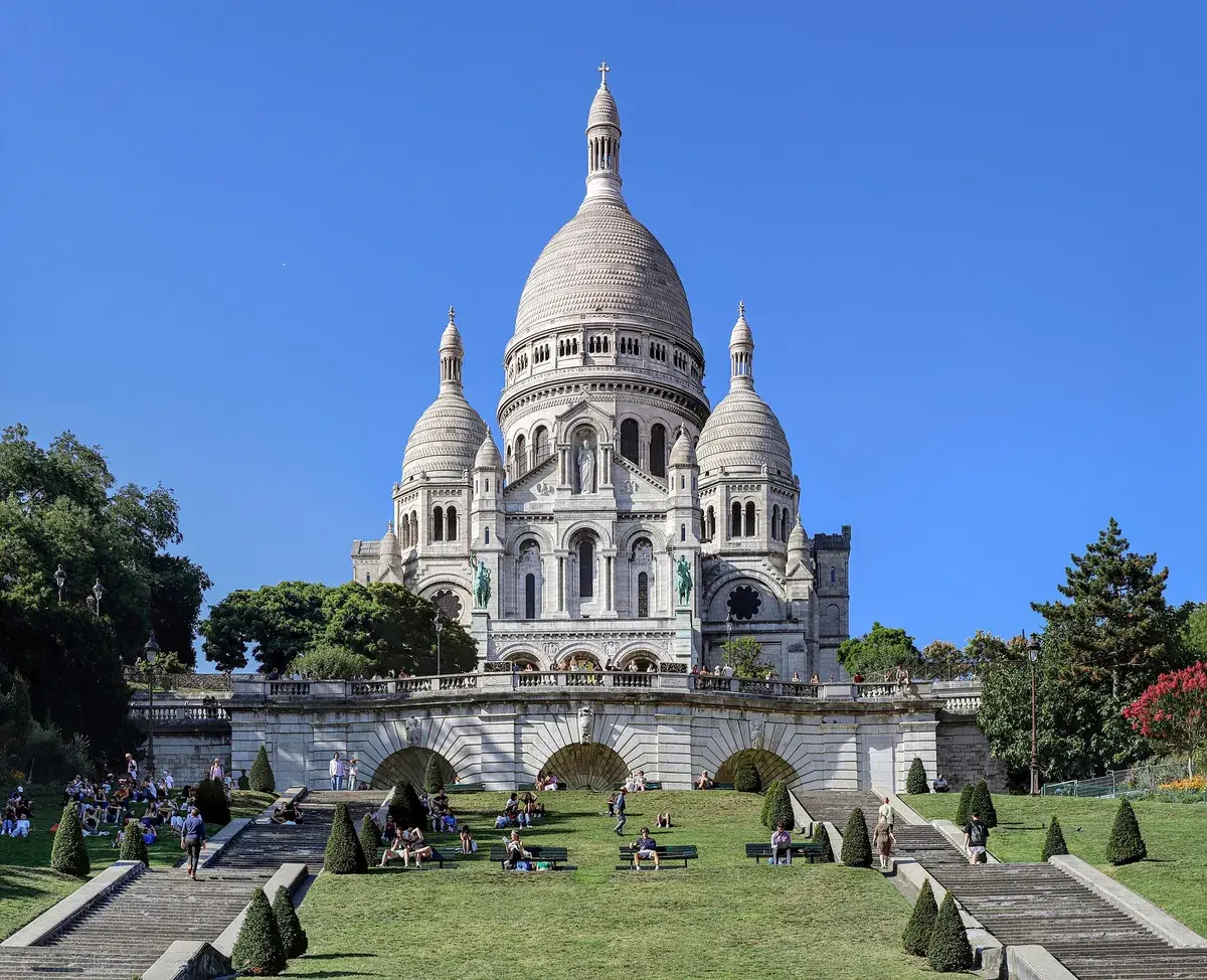 The white domes of the Sacré-Cœur basilica above the green slope of Montmartre. Photo: Giò Terra, CC BY-SA 4.0